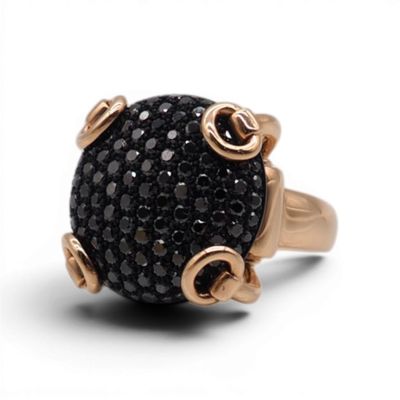 une image représentant une bague noire et dorée ornée de pierres noires