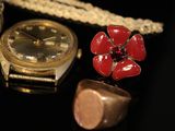 a gold watch and a red flower on a black surface