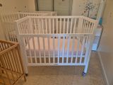 un lit de bébé dans un coin d'une pièce, avec un autre lit de bébé à côté