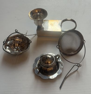 une théière et une passoire à thé posées sur une table