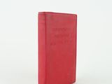 an old red book sitting on top of a white surface