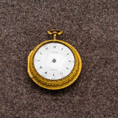 une montre de poche en or avec un cadran blanc sur un fond marron