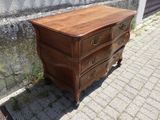 une commode en bois posée sur un trottoir en briques