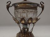 a silver and glass vase with a bird on it