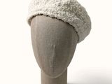 un chapeau blanc posé sur la tête d'un mannequin, sur fond blanc