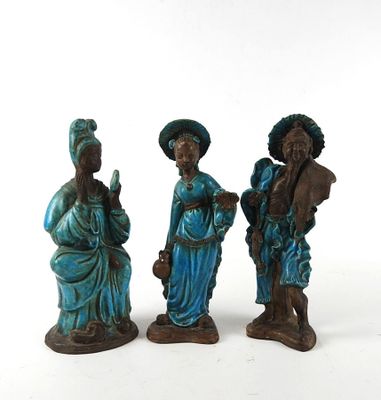 three figurines of people standing next to each other on a white surface