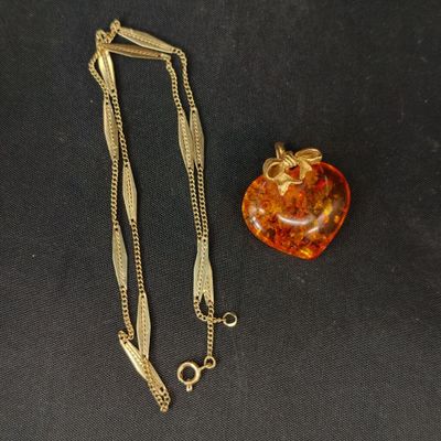 une image représentant un collier et une pomme sur un fond noir