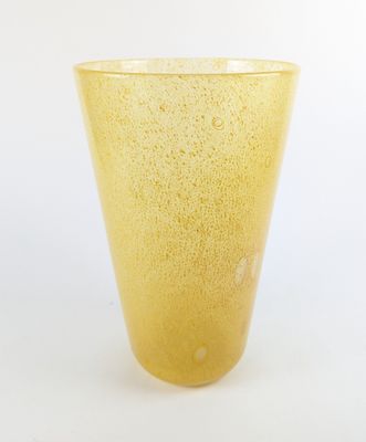 un vase en verre jaune posé sur une surface blanche