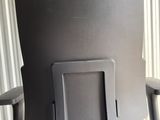 the back of a black office chair sitting in front of a curtain