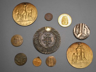 several coins and a medal on a table with a gray background