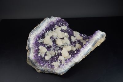 un gros plan sur un morceau de roche violette et blanche posé sur une surface noire