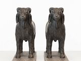 deux statues de moutons placées l'une à côté de l'autre sur une surface blanche