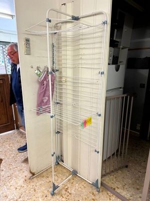 un homme debout à côté d'un portemanteau métallique sur lequel sont suspendus des vêtements