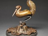 sculpture of a pelican sitting on a leaf on a base
