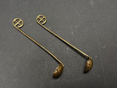 a pair of brass spoons on a black surface