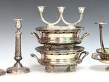 quatre chandeliers en argent et un bol posés sur une table