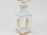 a clear glass bottle with a gold decoration on it