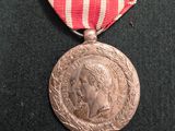 une médaille d'argent entourée d'un ruban rouge et blanc