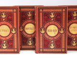 trois livres sont alignés sur une surface blanche