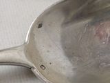 a silver spoon with a handle on a white surface