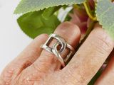 a person holding a ring in their hand with a flower in the background