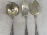 three silver spoons and a spoon on a white surface