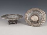 two silver dishes and a bowl on a stand on a white surface