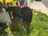 a plow sitting in the grass on the side of the road
