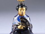 a small glass figurine of a woman holding a fan