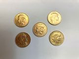 quatre types différents de pièces d'or sur une surface blanche