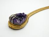 un améthorate violet dans une cuillère en or posée sur une surface blanche
