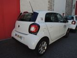 a small white car parked next to a red wall