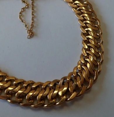 gros plan d'un collier à chaîne en or sur une surface blanche