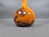 a small orange vase sitting on a gray surface