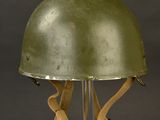 an old green helmet on a clear stand against a black background