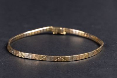 gros plan d'un bracelet en or sur une surface noire