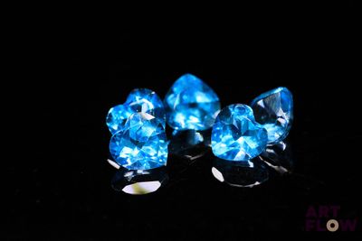 three pieces of blue topazte sit on a black surface