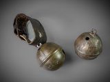 pair of bronze bells with a leather strap on each side