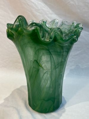 a green vase that is sitting on a white cloth