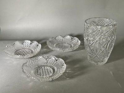 four glass bowls and two vases on a table