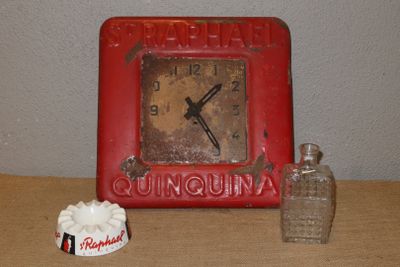 une horloge rouge posée sur une table, à côté d'une tasse de café