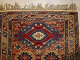an image of a red, blue, and yellow rug with fringes on it