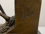 a bronze sculpture of a bird on a stand