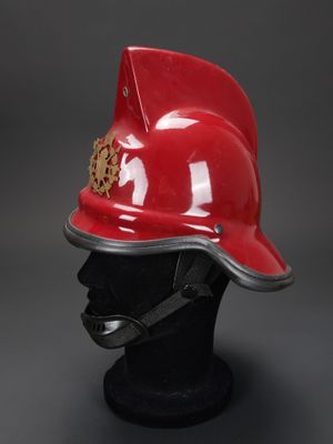 un casque de pompier rouge posé sur une tête de mannequin noire