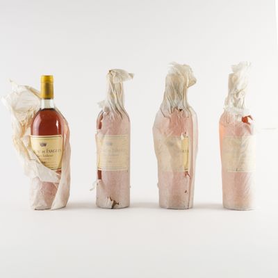quatre bouteilles de vin emballées dans du film plastique, avec une bouteille de vin en arrière-plan