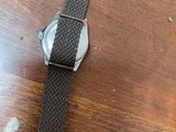 watch on a wooden table with a black strap around the wrist