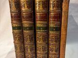 quatre vieux livres posés l'un sur l'autre sur une surface blanche