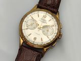 gros plan d'une montre sur une surface blanche avec un bracelet marron