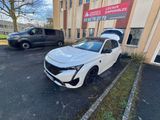 une voiture blanche garée devant un immeuble, à côté d'un parking