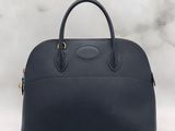 a navy blue leather handbag on a marble background